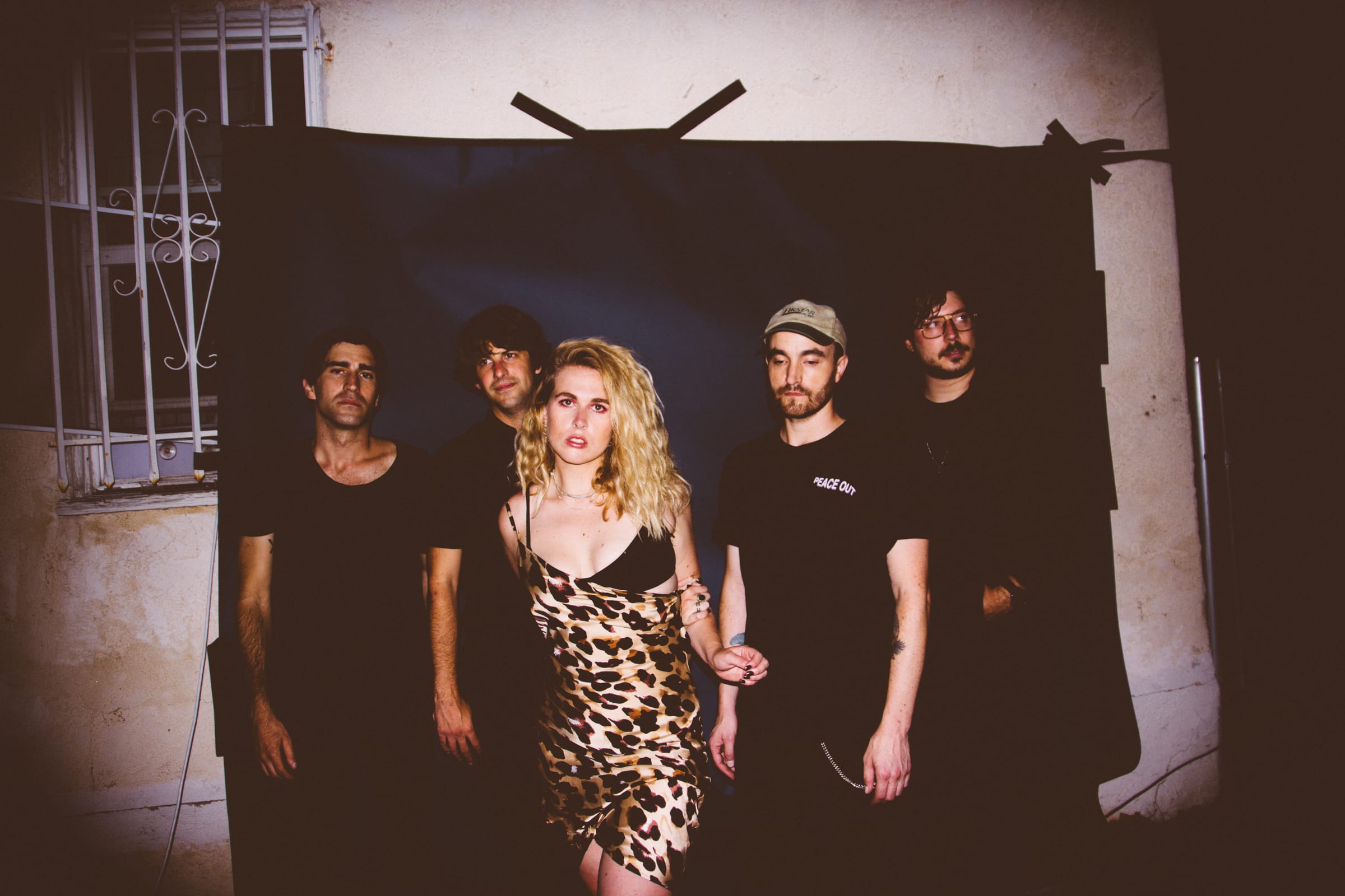 five band members of The Dumes stand in front of the a makeshift backdrop