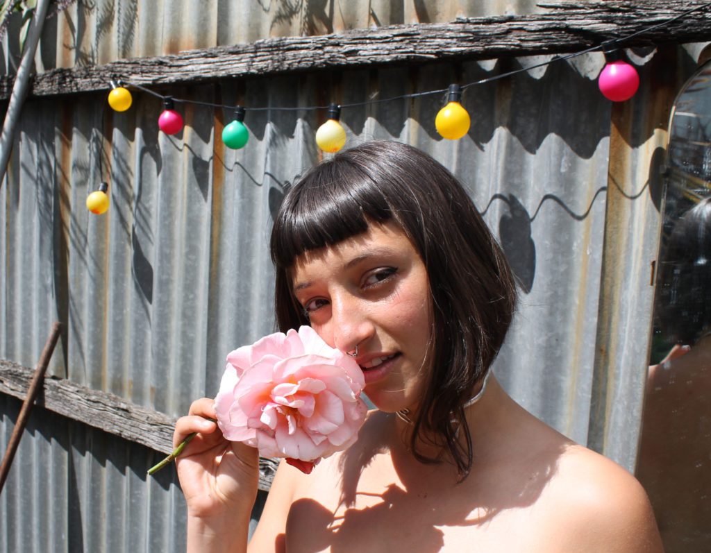 musician Juman holds a large flower to her face