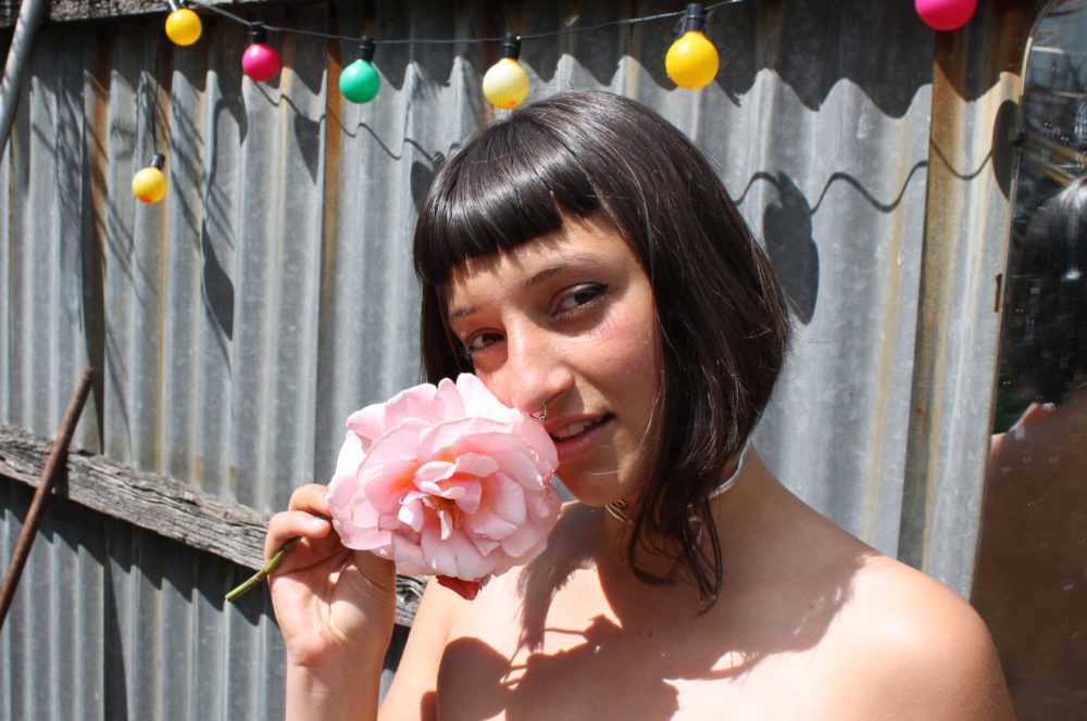 musician Juman holds a large flower to her face